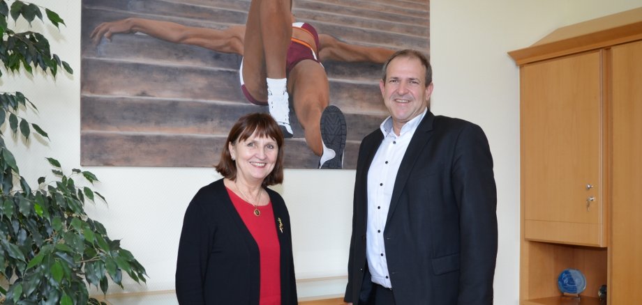The photo shows the artist Luise Schwarz and Lord Mayor Frank Frühauf in front of the painting 'Sportlerin'.