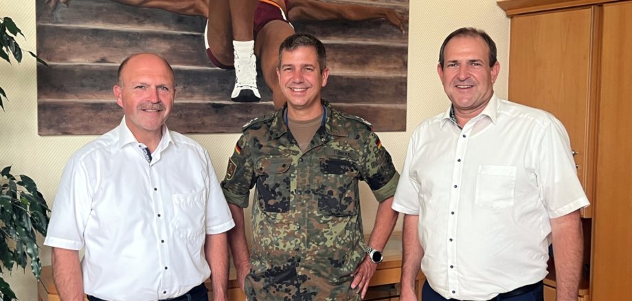 The photo shows, from right to left, Mayor Frank Frühauf, Colonel Olaf Tuneke and Mayor Friedrich Marx standing in front of a wall with a painting in Mayor Frühauf's office and looking into the camera.
