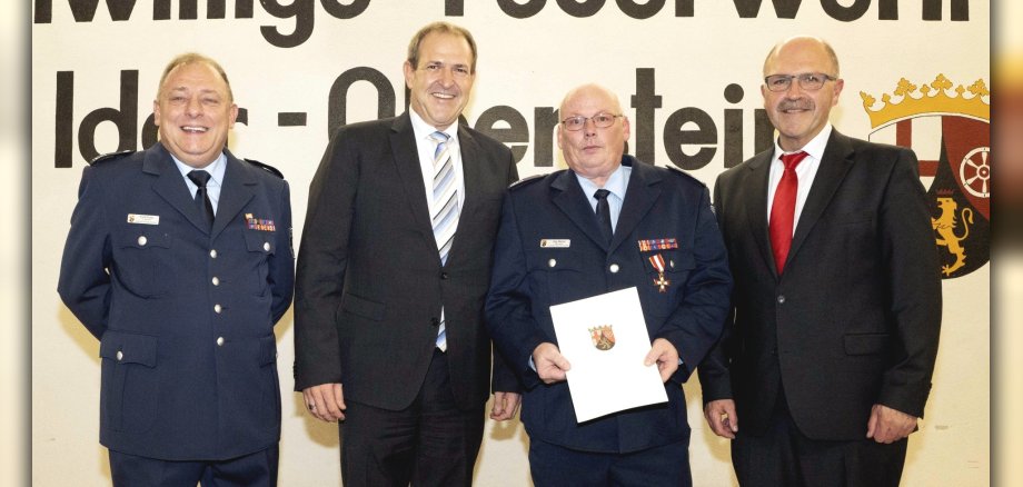 The photo shows deputy chief of guard Frank Knapp, Lord Mayor Frank Frühauf, chief of the fire brigade Jörg Riemer and Mayor Friedrich Marx standing next to each other on the stage. Jörg Reimer holds a certificate in his hand.