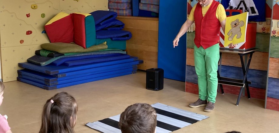 The picture shows the wizard Robert standing in front of a stylized crosswalk and explaining to the children at the daycare center what to do.