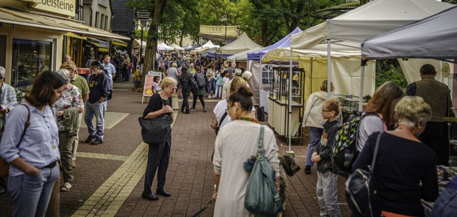 The photo shows a view of the main street in the Oberstein district during the gemstone cutters' and goldsmiths' market. You can see many people walking through the street or standing in front of the exhibitors' pavilions.