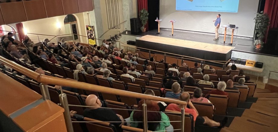 The photo shows the lower section of the theater hall in the Stadttheater, which is well occupied for the information event.