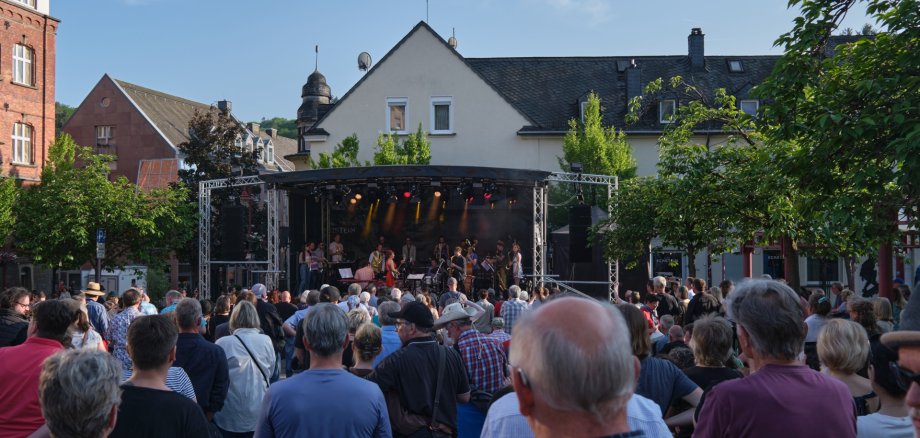 The photo shows the stage on the market square in the background, with many people in front of it.
