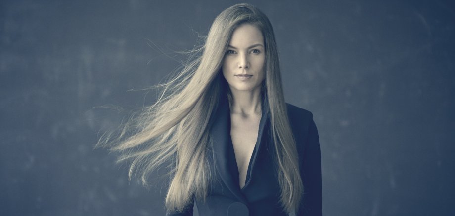 La photo montre la chanteuse Rebekka Bakken, les cheveux longs au vent, sur un fond gris.