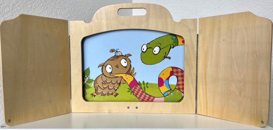 La photo montre un cadre en bois du Kamishibai avec une illustration colorée d'un hibou.