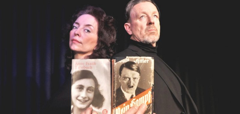 La photo montre les deux acteurs dos à dos devant un rideau de scène noir. Marianne Blum tient le journal d'Anne Frank, Thomas Linke le Mein Kampf d'Adolf Hitler.