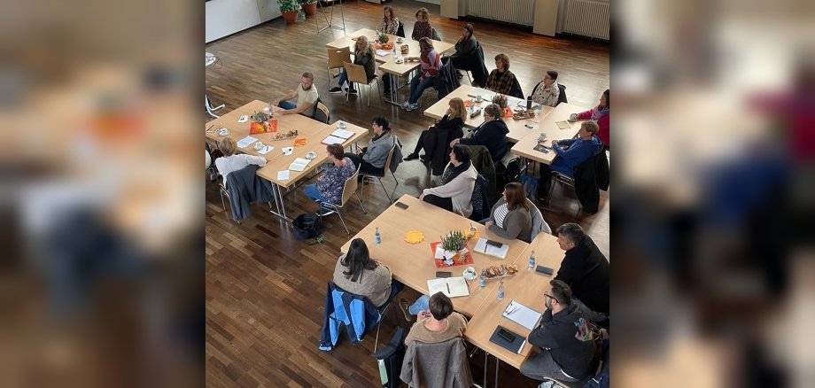 La photo montre une vue d'en haut des participants à la conférence dans l'aula Göttenbach. Ils sont assis à plusieurs tables.