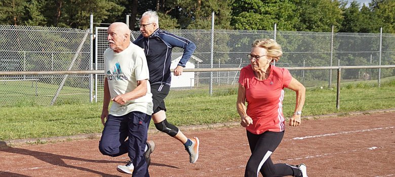La photo montre trois participants plus âgés sur la piste d'athlétisme.