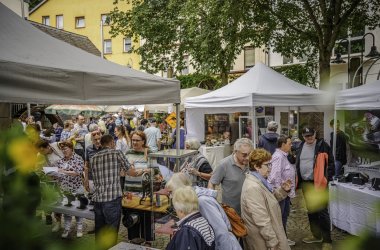 Das Foto zeigt einen Blick auf Stände des Edelsteinschleifer- und Goldschmiedemarktes mit zahlreichen Besuchern.