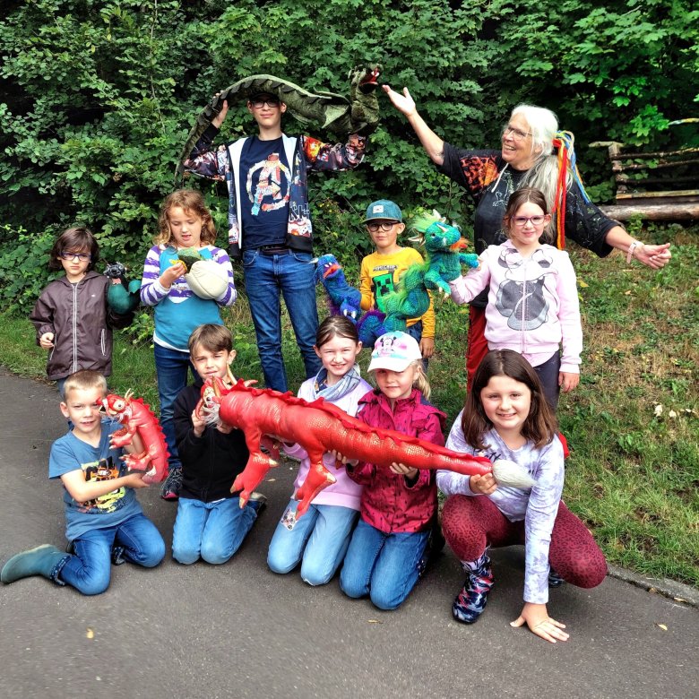 Das Foto zeigt die Teilnehmer mit Gaby Hofmann. Sie halten Drachenfiguren in den Händen. 