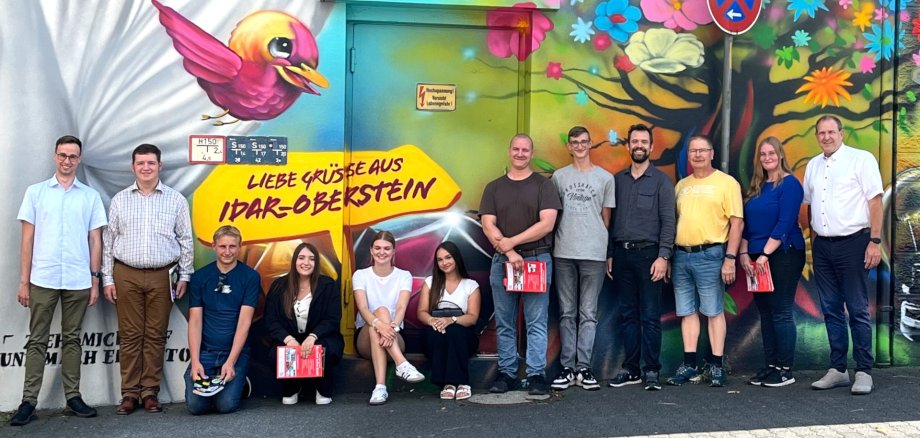 Das Foto zeigt die Azubis und Vertreter der Verwaltung an dem neuen Fotopoint am Bahnhof Idar-Oberstein.