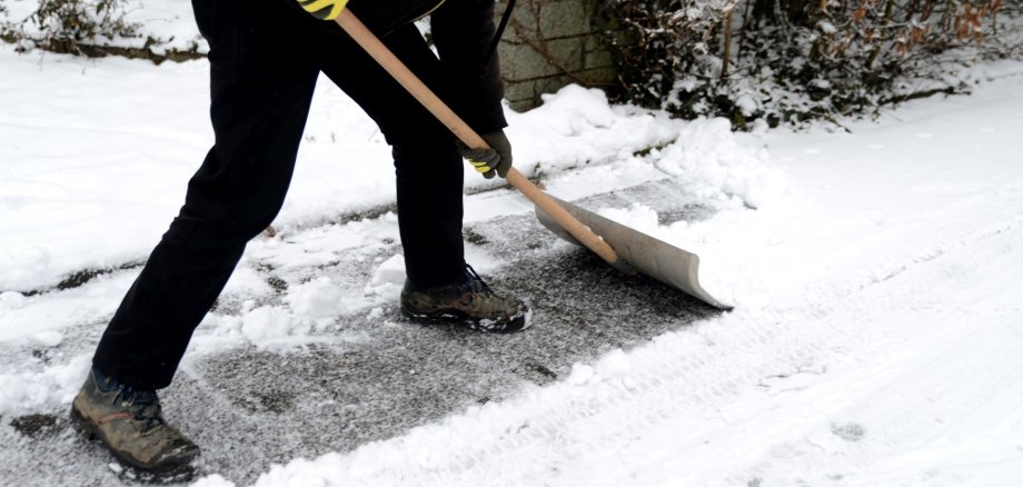 Das Foto zeigt eine Person beim Schnee räumen.