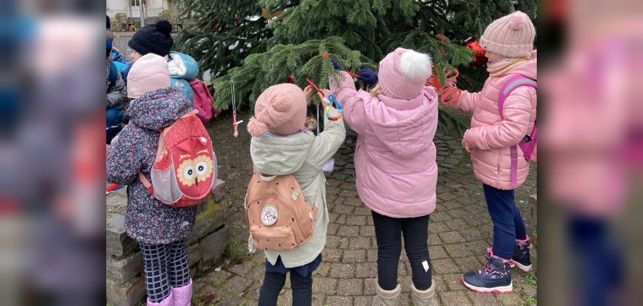 Das Foto zeigt vier Kinder beim Schmücken des Weihnachtsbaums.