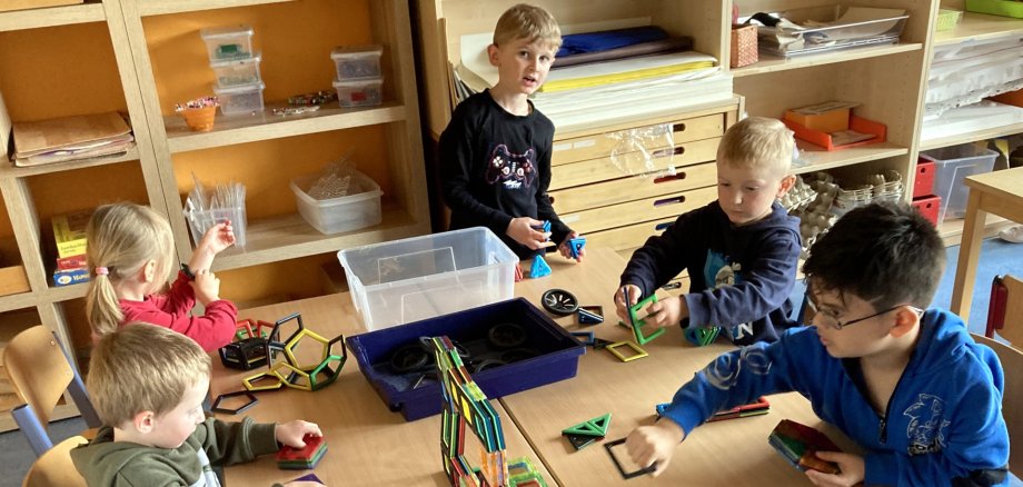 Das Foto zeigt Kinder, die an einem Tisch sitzen und mit Magnetbausteinen spielen.