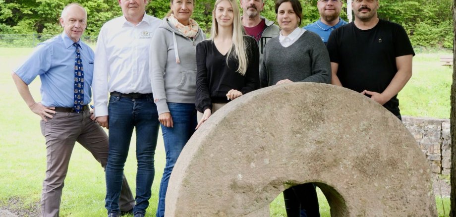 Das Foto zeigt die Organisatoren vor Ort, acht Personen, die an der Weiherschleife am Schleifstein stehen. 