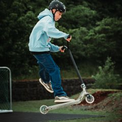Das Foto zeigt einen Jungen mit dem Roller auf der Skateranlage.