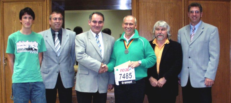 Das Foto aus dem Jahr 2005 zeigt insgesamt sechs Personen, die im Büro des damaligen Bürgermeisters Peter Simon nebeneinander stehen und in die Kamera schauen. Rainer Hagner schüttelt dem Bürgermeister die Hand. 
