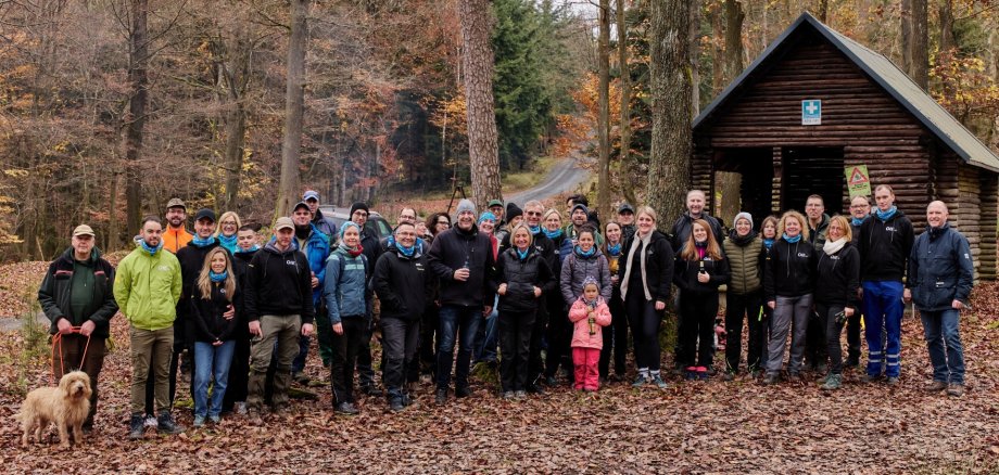 Das Foto zeigt die Teilnehmer der Pflanzaktion. Sie stehen vor einer Schutzhütte im Wald in zwei Reihen nebeneinander und blicken in die Kamera.