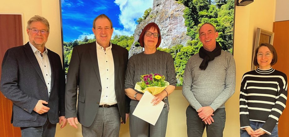 Das Foto zeigt fünf Personen, die nebeneinander stehen und in die Kamera schauen. Frau Schöfferle steht in der Mitte und hält einen Blumenstrauß in der Hand.