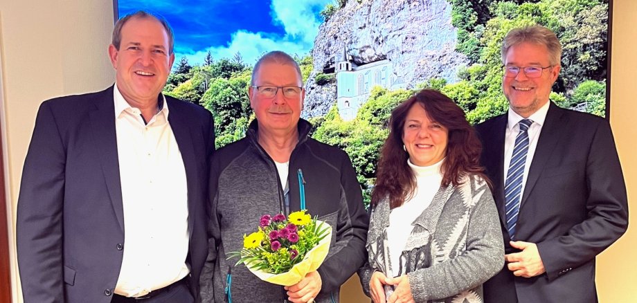 Das Foto zeigt die genannten Personen. Sie stehen nebeneinander vor einem Bild der Felsenkirche und blicken in die Kamera. Volker Poeß hält einen Blumenstrauß in der Hand.