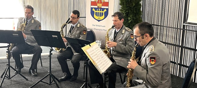 Das Foto zeigt die vier Musiker. Sie sitzen mit ihren Instrumenten auf der Bühne und spielen.